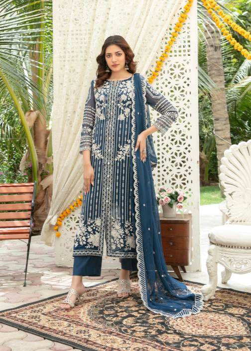 Woman in a blue and white traditional outfit standing outdoors with decorative elements.