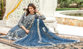 Woman in a blue and white traditional outfit sitting on a decorative chair outdoors.