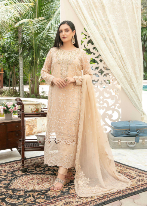 Woman in a beige embroidered outfit standing in a decorated outdoor setting with palm trees and a pool.