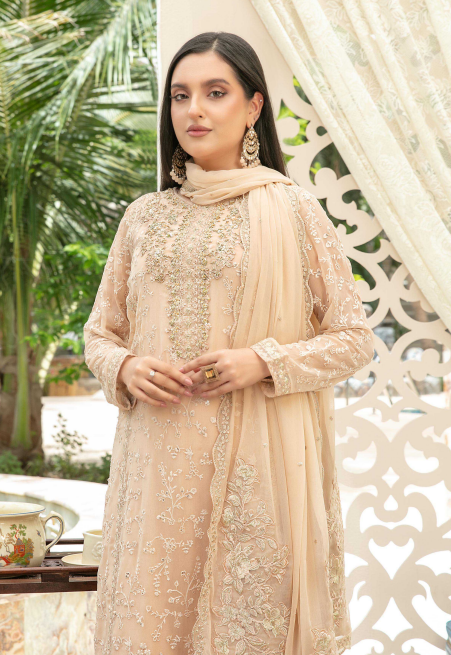Woman in a beige embroidered outfit with a matching dupatta, standing outdoors.