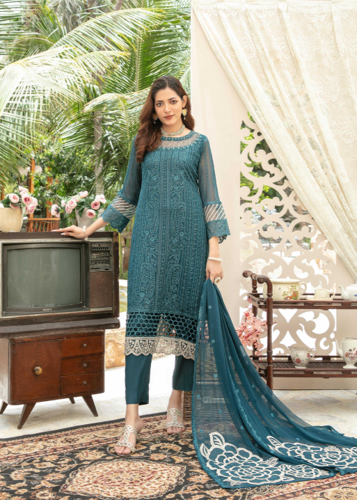 Woman in a teal embroidered outfit standing in a decorated room with a vintage television.
