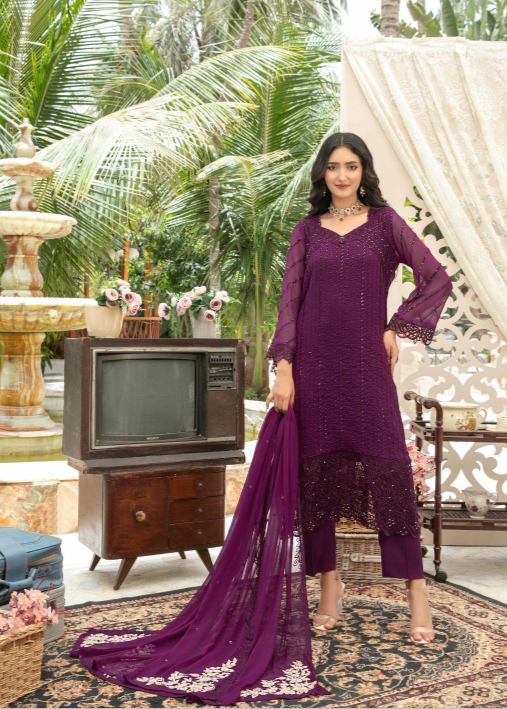 Woman in a purple outfit standing in a decorative outdoor setting with palm trees and a vintage television.