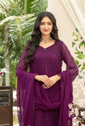 Woman in a purple traditional outfit standing outdoors with greenery in the background