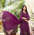 Woman in a purple traditional outfit with a matching dupatta, standing outdoors.