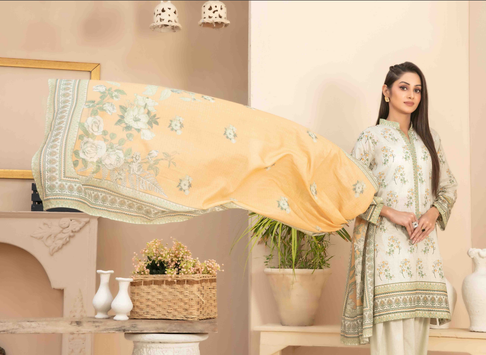 Woman in a floral outfit standing next to a large yellow fabric with floral patterns in a decorated room.