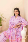 Woman wearing a pink traditional outfit with floral patterns indoors.