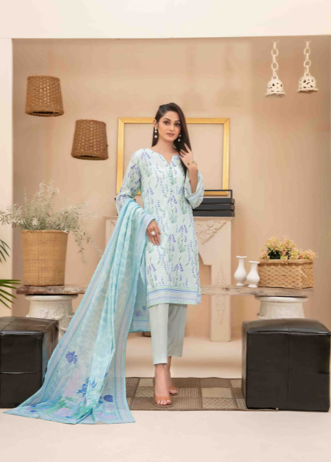 Woman in a light blue embroidered outfit standing in a decorated room.
