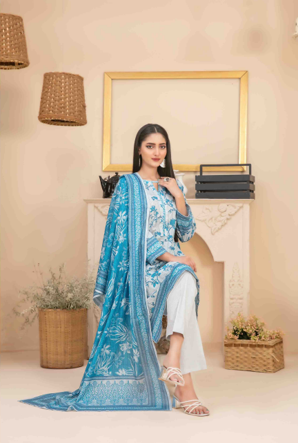 Woman in a blue floral outfit sitting on a chair with a beige wall and decorative items in the background.