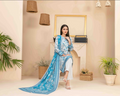Woman in a blue and white traditional outfit sitting in a stylish room with plants and decor.