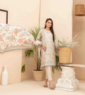 Woman in a floral dress standing in a room with plants and a bed.