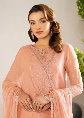Woman wearing a peach-colored traditional outfit with intricate designs.