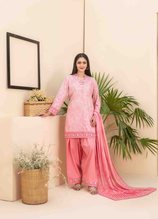 Woman in a pink traditional outfit standing in a room with plants and a mirror.