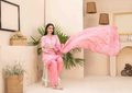 Woman in a pink traditional outfit holding a pink scarf in a home setting.