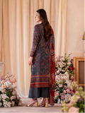Woman in a patterned dress standing in front of floral decorations and curtains.