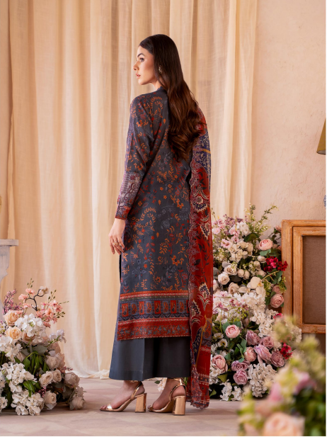 Woman in a patterned dress standing in front of floral decorations and curtains.