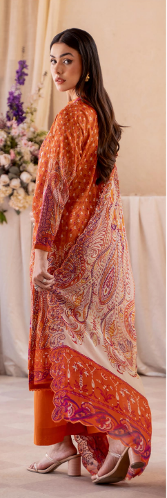 Woman wearing an orange and red patterned outfit with a matching shawl indoors.