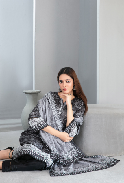 Woman wearing a black and white patterned dress sitting on a gray couch.