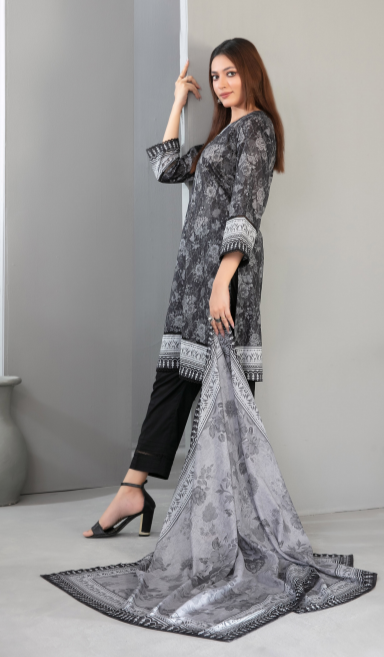 Woman wearing a black and white patterned outfit with a matching scarf on a gray background