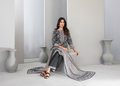 Woman in a gray and white patterned outfit sitting on a white floor with vases in the background.