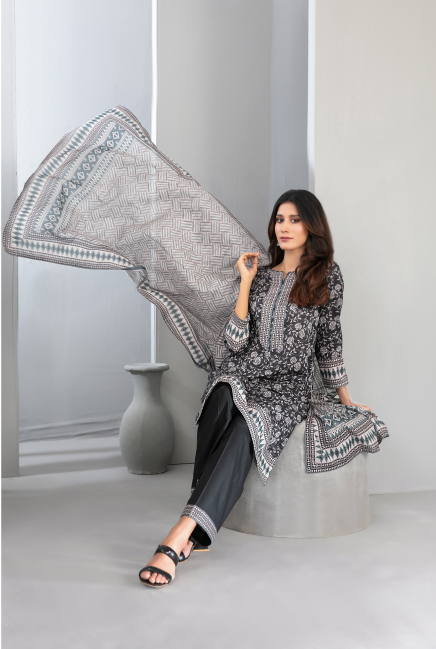 Woman holding a large patterned scarf in a minimalistic setting