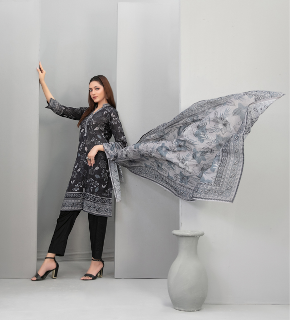 Woman in a black floral outfit with a matching scarf against a gray background