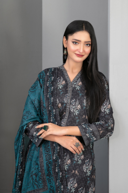 Woman wearing a dark floral dress with a teal shawl against a gray background