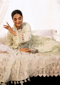 Woman in a white embroidered traditional outfit sitting on a white couch.