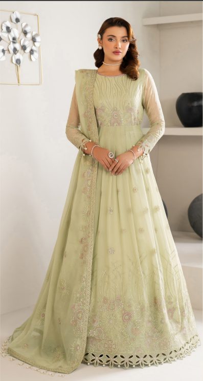 Woman wearing a light green traditional outfit with intricate designs indoors.