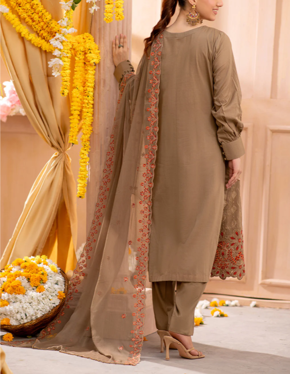 Woman wearing a beige traditional outfit with floral embroidery in a decorated setting.
