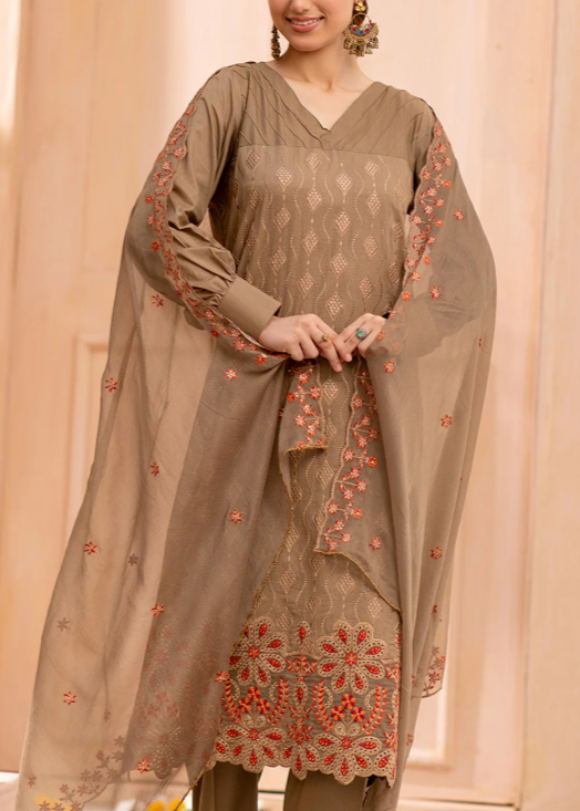 Woman wearing a brown embroidered traditional outfit against a beige background