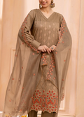 Woman wearing a brown embroidered traditional outfit against a beige background