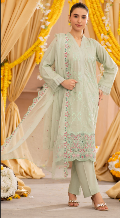 Woman in a light green traditional outfit with floral patterns against a decorated background