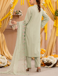 Woman in a light green traditional outfit with a floral dupatta against a decorated backdrop.