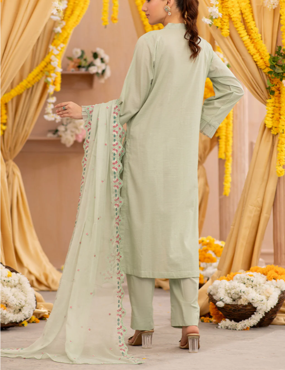 Woman in a light green traditional outfit with a floral dupatta against a decorated backdrop.