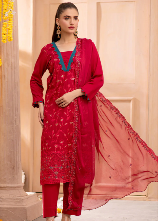 Woman wearing a red traditional outfit with a pink dupatta in a decorated indoor setting.