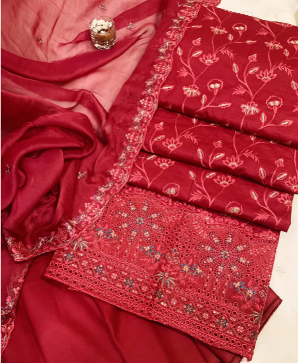 Red embroidered fabric with intricate patterns on a beige background