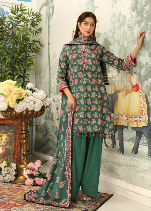 Woman in a green floral outfit standing in a decorated room with flowers and a painting.