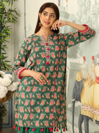 Woman wearing a green floral dress with red accents, standing indoors.